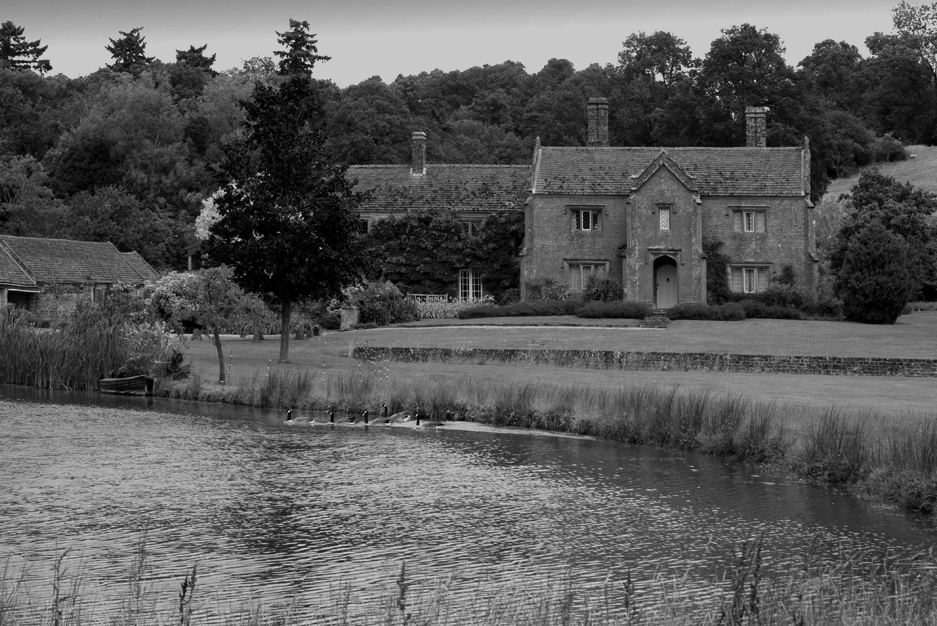 A large country house with a lake in the foreground.